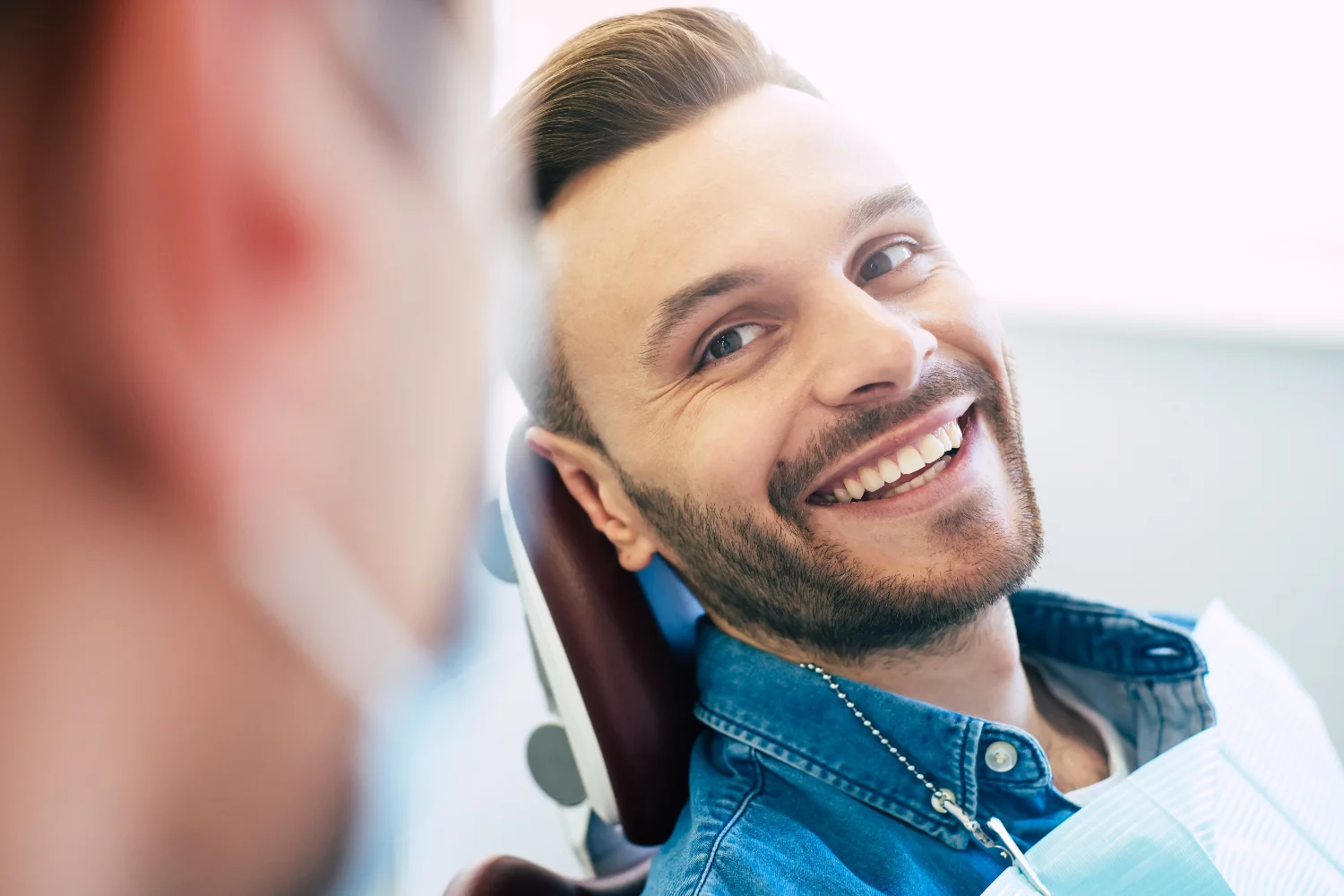 Man with beard smiling to her dental professional in a dental practice